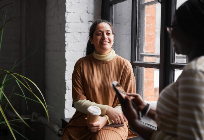 Ethnic Businesswomen Communicating Portrait of Middle-Eastern businesswoman talking to colleague while discussing project in modern office interior, copy space
